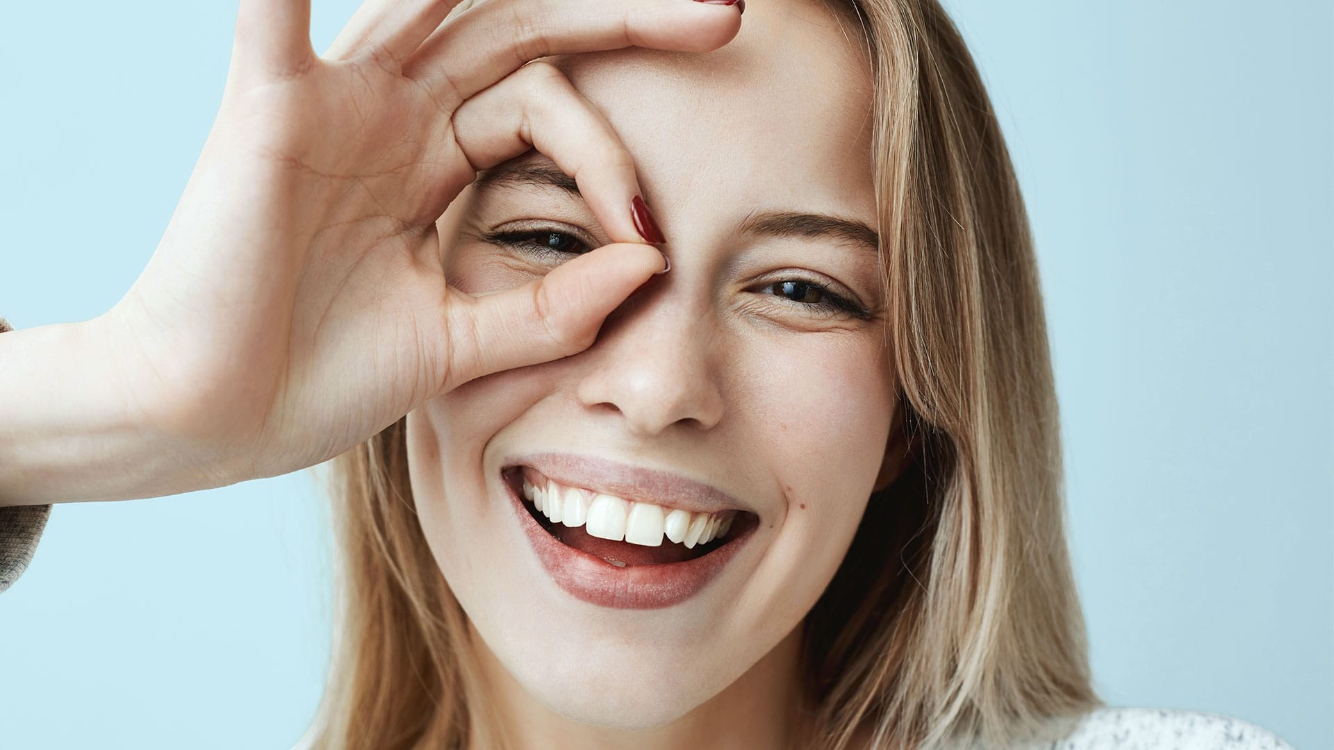Chica sonriente mirando a través de sus dedos